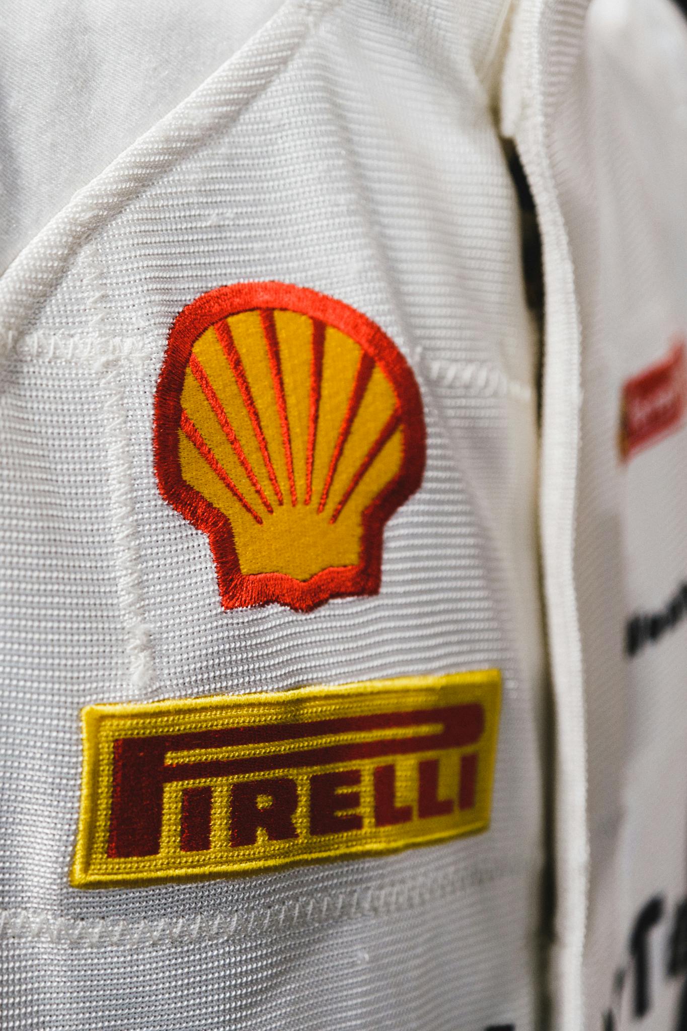 Detailed view of a racing suit featuring Shell and Pirelli brand logos.